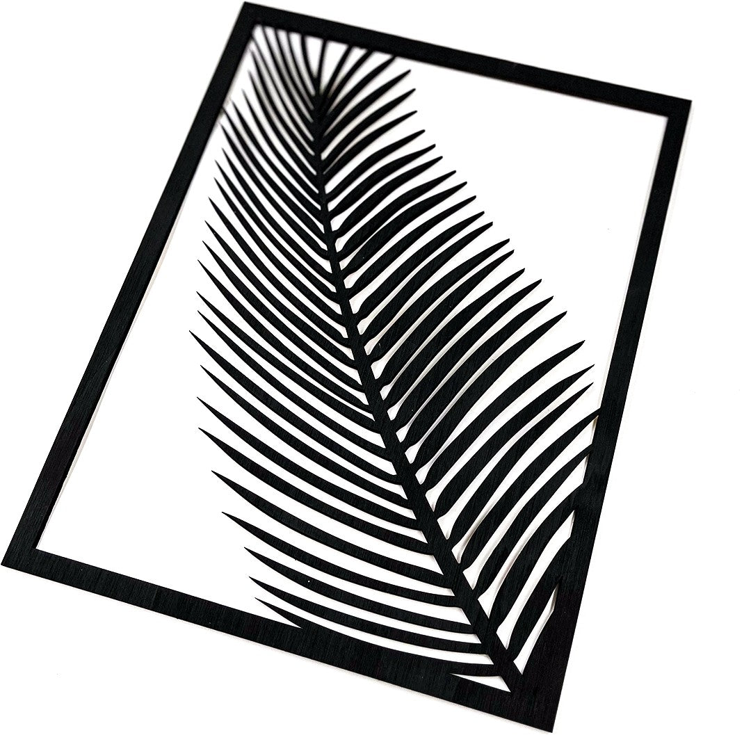 Wooderland wooden wall decor featuring a black carved palm leaf design in a rectangular frame on a white background.