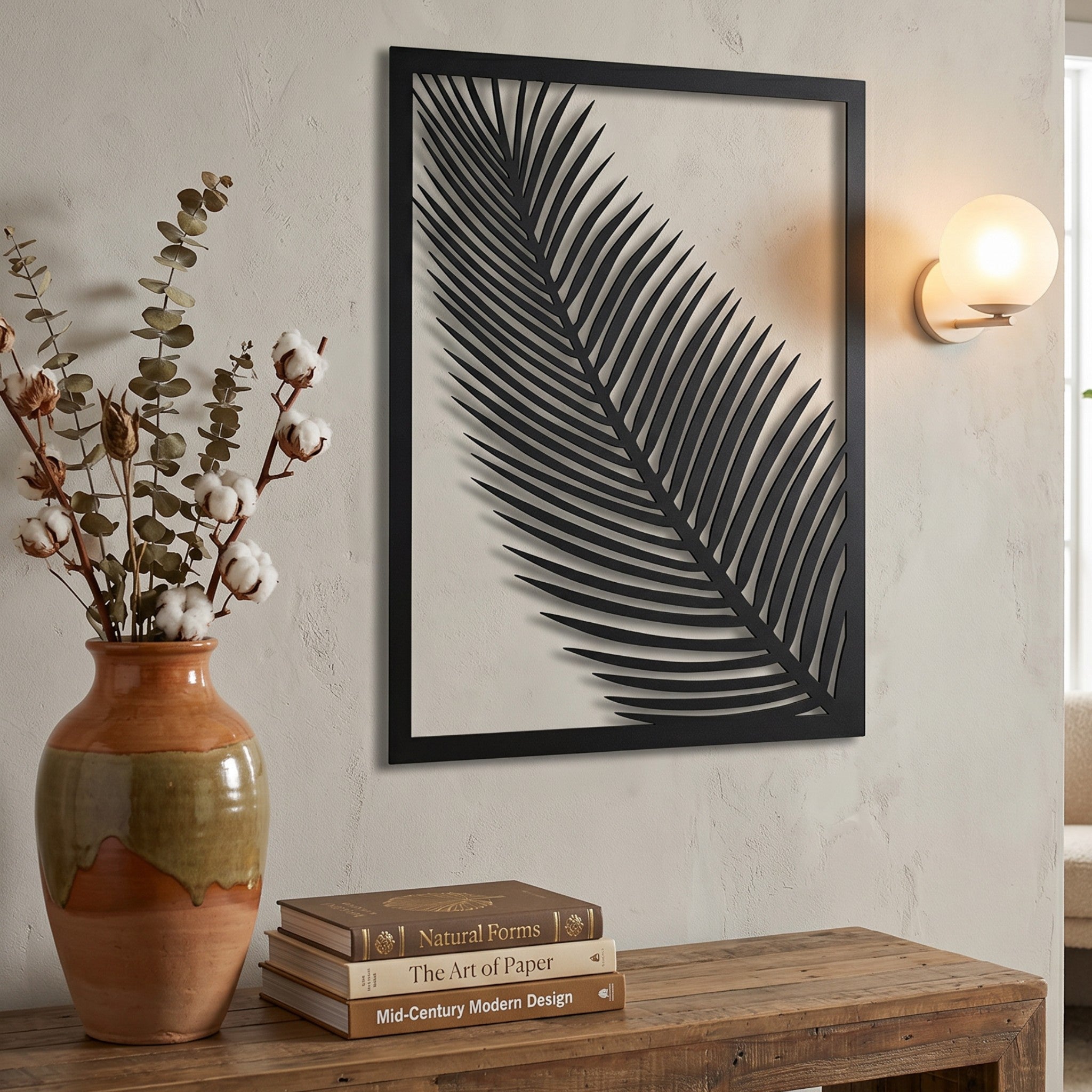 Wooderland black wooden leaf wall art in a rectangular frame hanging above a rustic wooden console table.