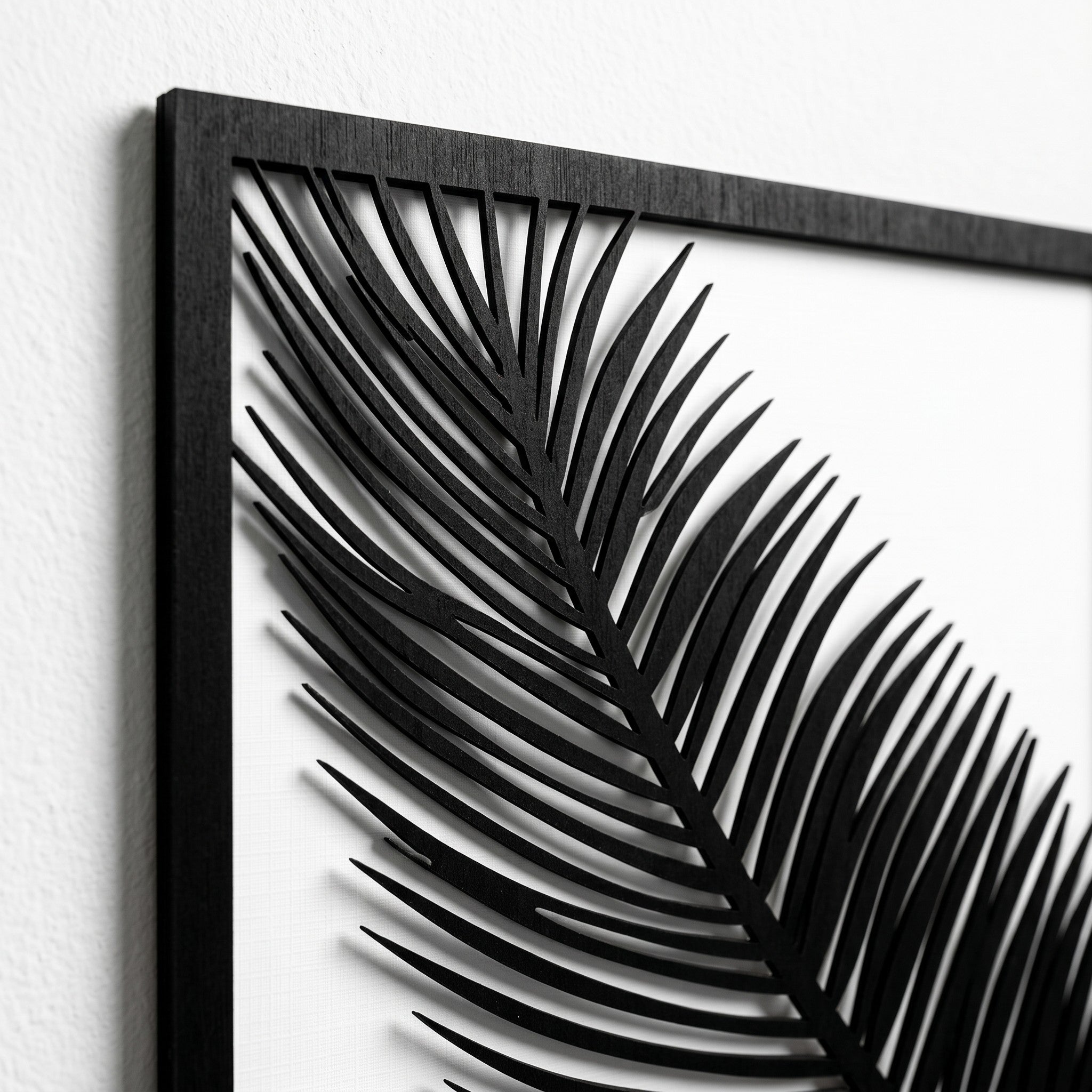 Wooderland black wooden wall decor featuring a detailed laser-cut palm leaf design on a white background