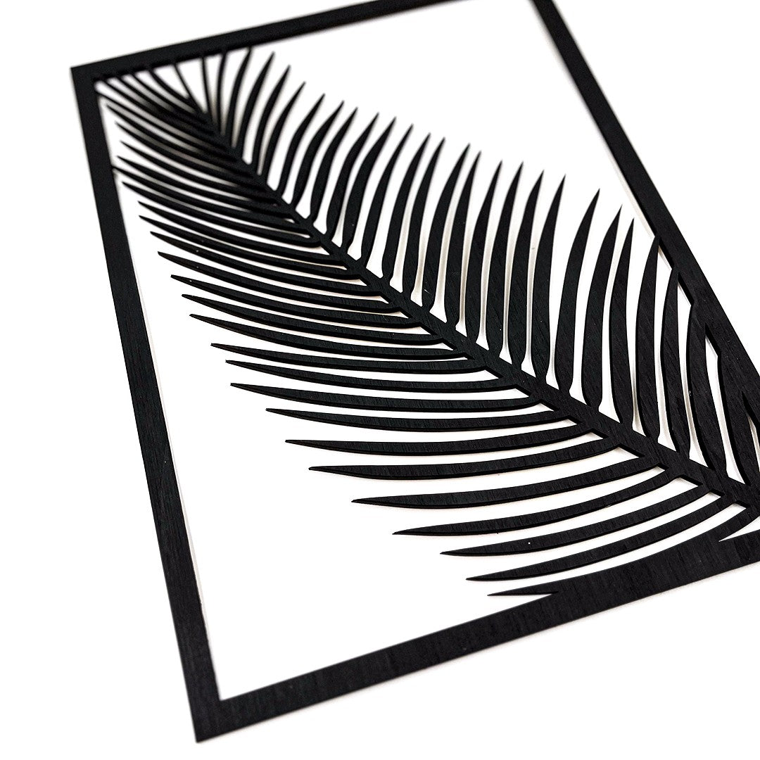 Wooderland black wooden wall decor featuring a laser-cut palm leaf design in a rectangular frame.