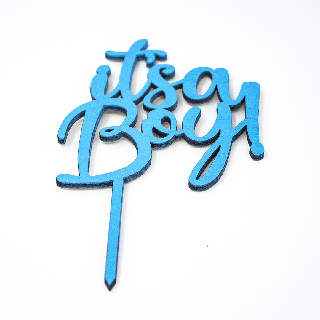 Wooderland blue wooden It's a Boy cake topper with laser-cut lettering for baby showers and gender reveals.