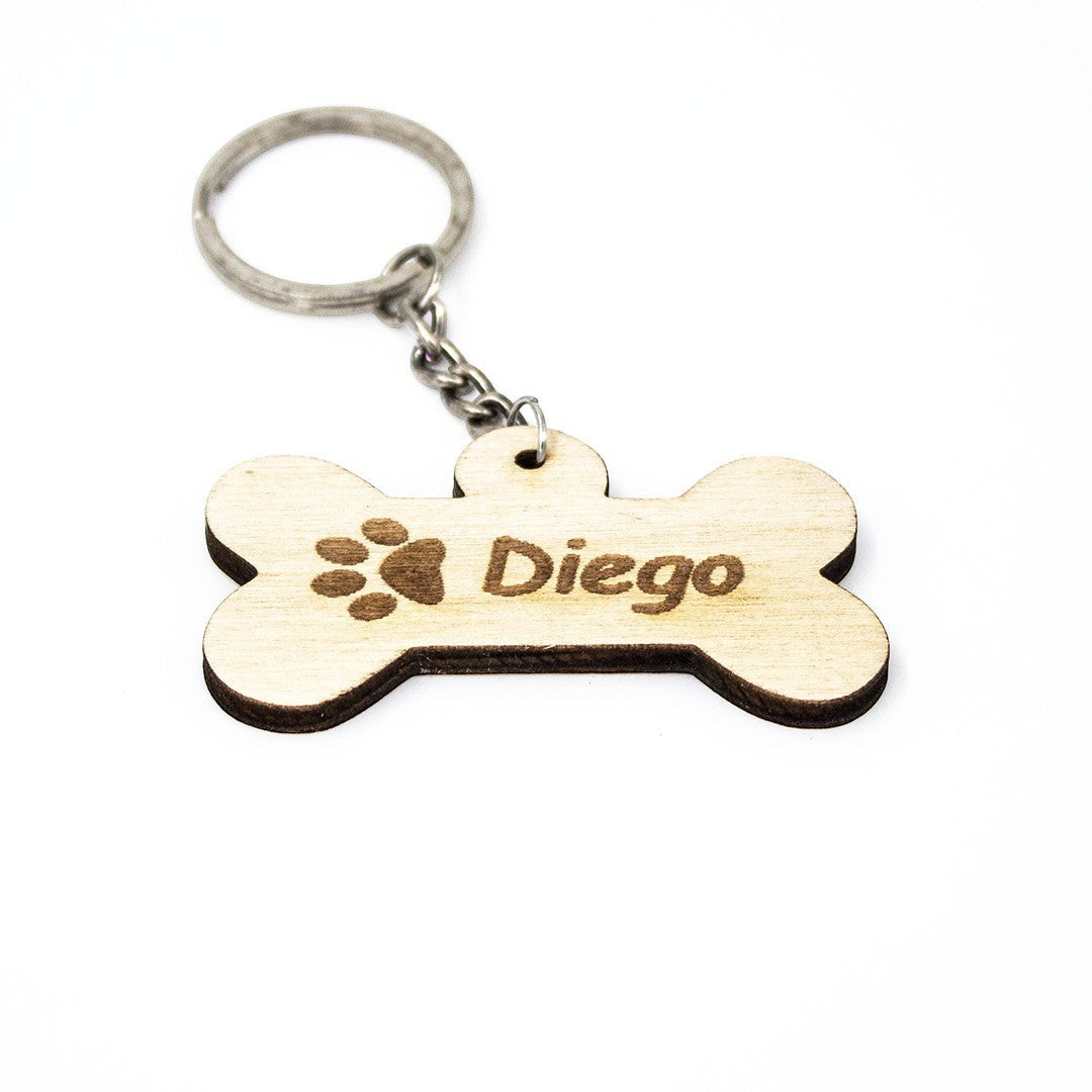 Wooderland bone-shaped wooden keyring engraved with a paw print and the name Diego on a white background