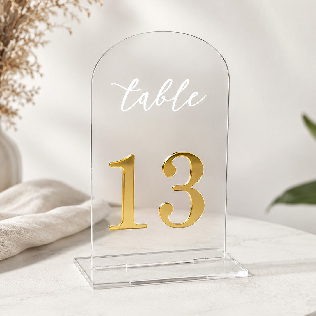 Wooderland clear acrylic arch wedding table number 13 with white script text and gold mirror acrylic digits.