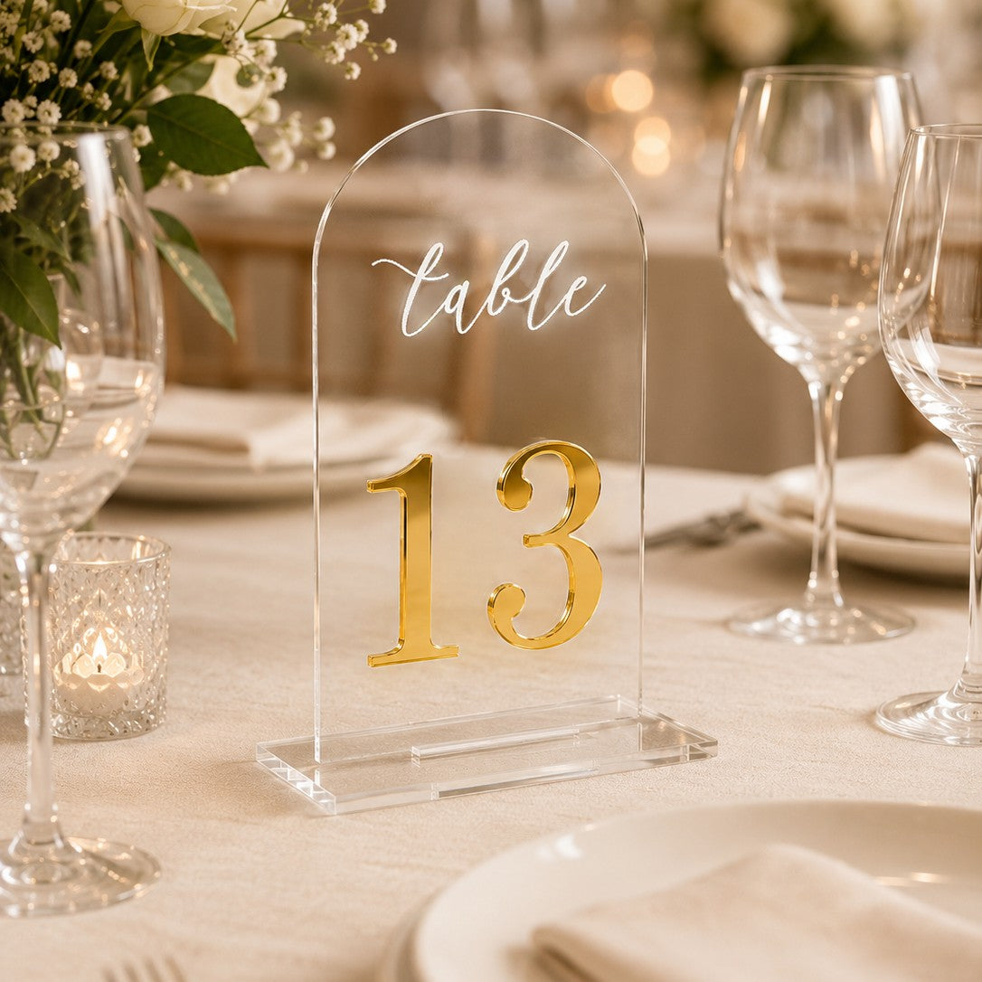 Wooderland clear acrylic arch table number 13 with gold mirror digits and white script on a wedding reception table