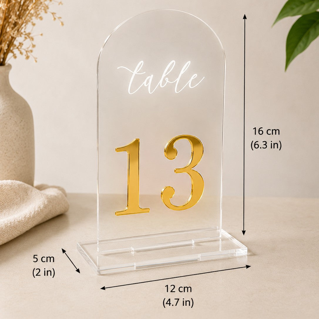 Wooderland clear acrylic arch wedding table number 13 with gold mirror digits and white script lettering on a base.