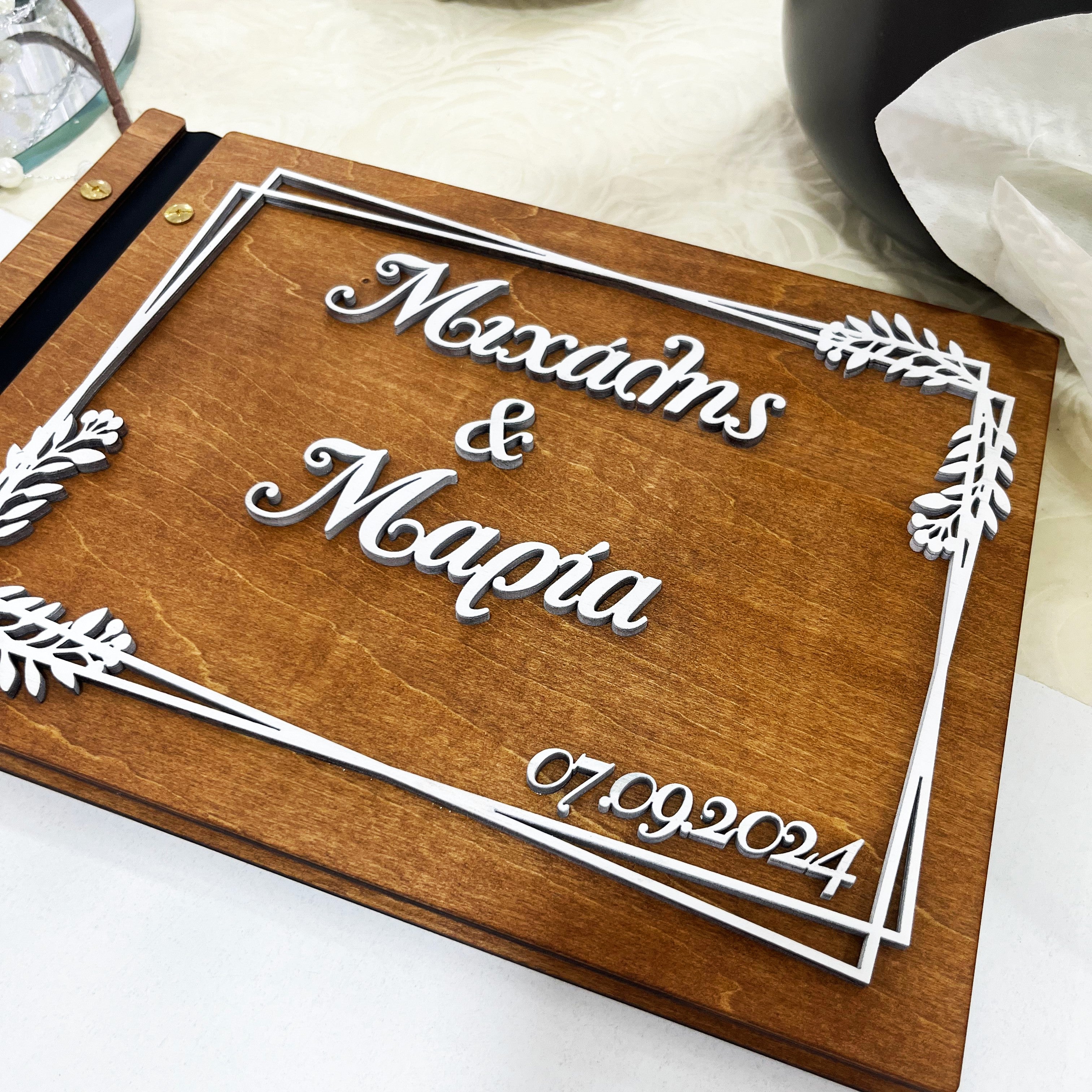 Wooderland custom engraved wooden wedding guest book with white 3D names and date on a dark wood cover.