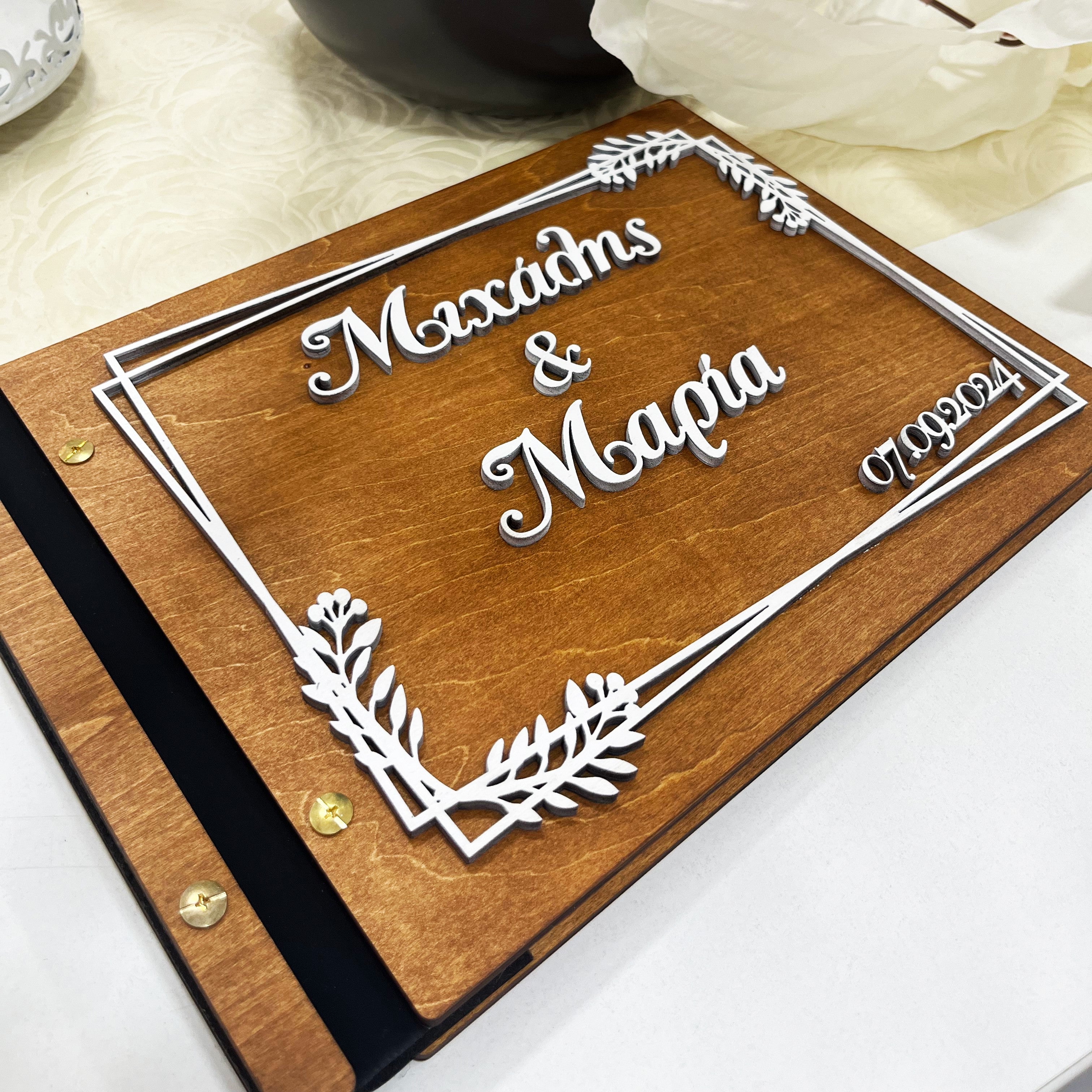 Wooderland custom engraved wooden wedding guest book with white 3D floral frame and personalized names and date.