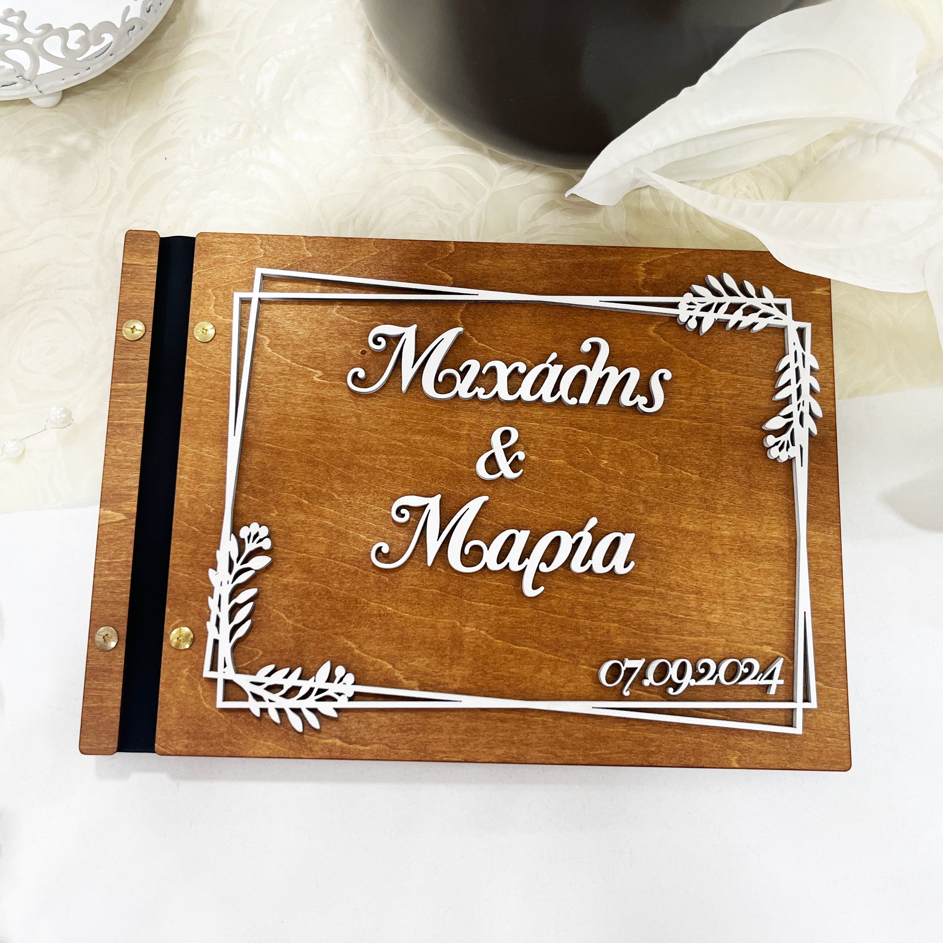 Wooderland custom engraved wooden wedding guest book with white 3D floral frame and personalized names and date.