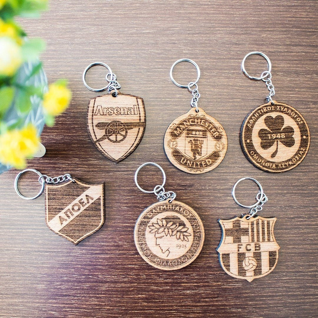 Wooderland customized wooden keyrings featuring various engraved sports team logos on a wooden surface.