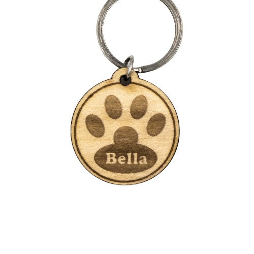Wooderland custom round wooden dog tag with engraved paw print and Bella name tag on a metal keyring