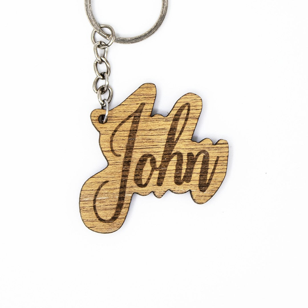 Wooderland custom wooden keyring with the name John engraved in elegant cursive script on a light wood finish.