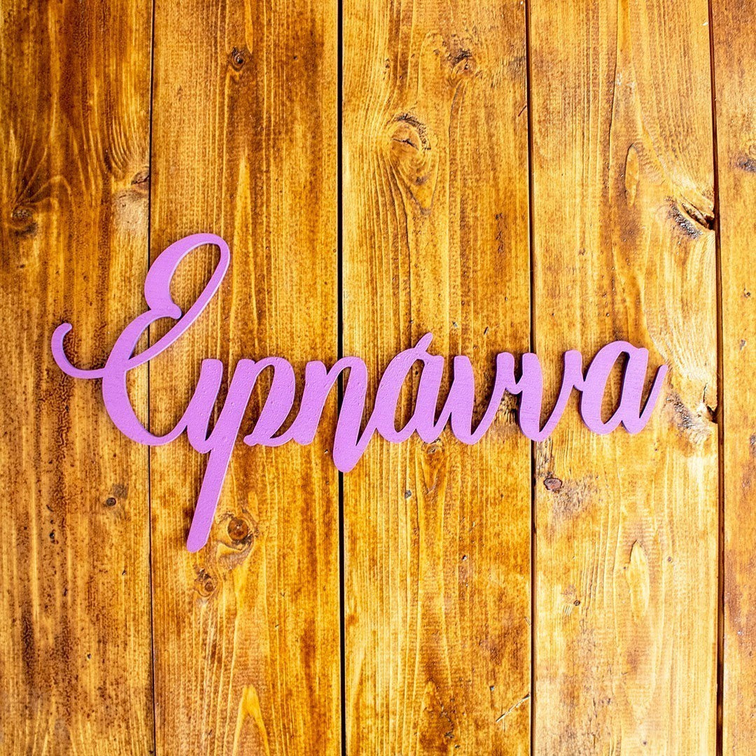 Wooderland custom laser-cut wooden name sign in purple script font displayed on a rustic wooden background