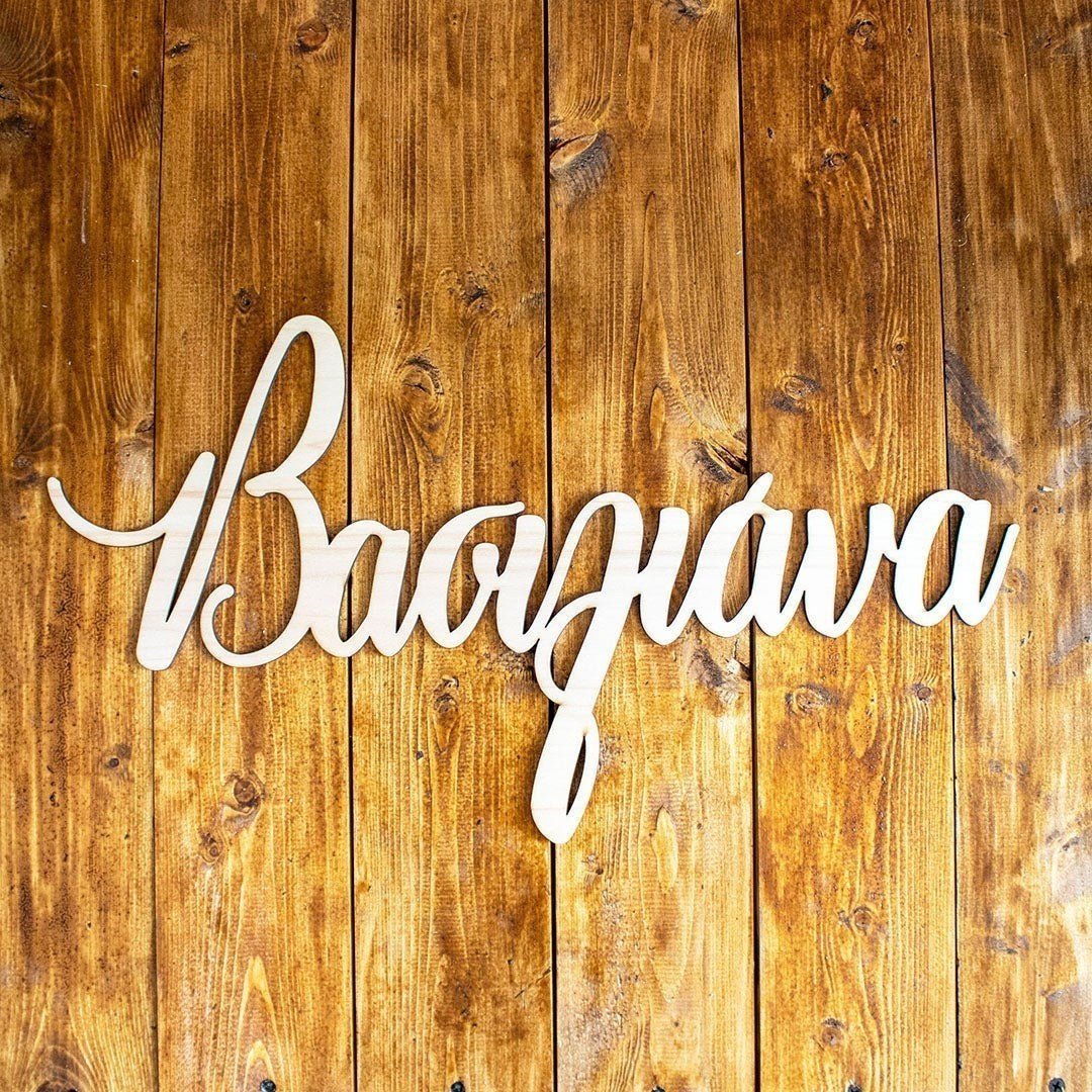 Wooderland custom laser-cut wooden name sign in raw plywood finish displayed on a rustic wooden background.