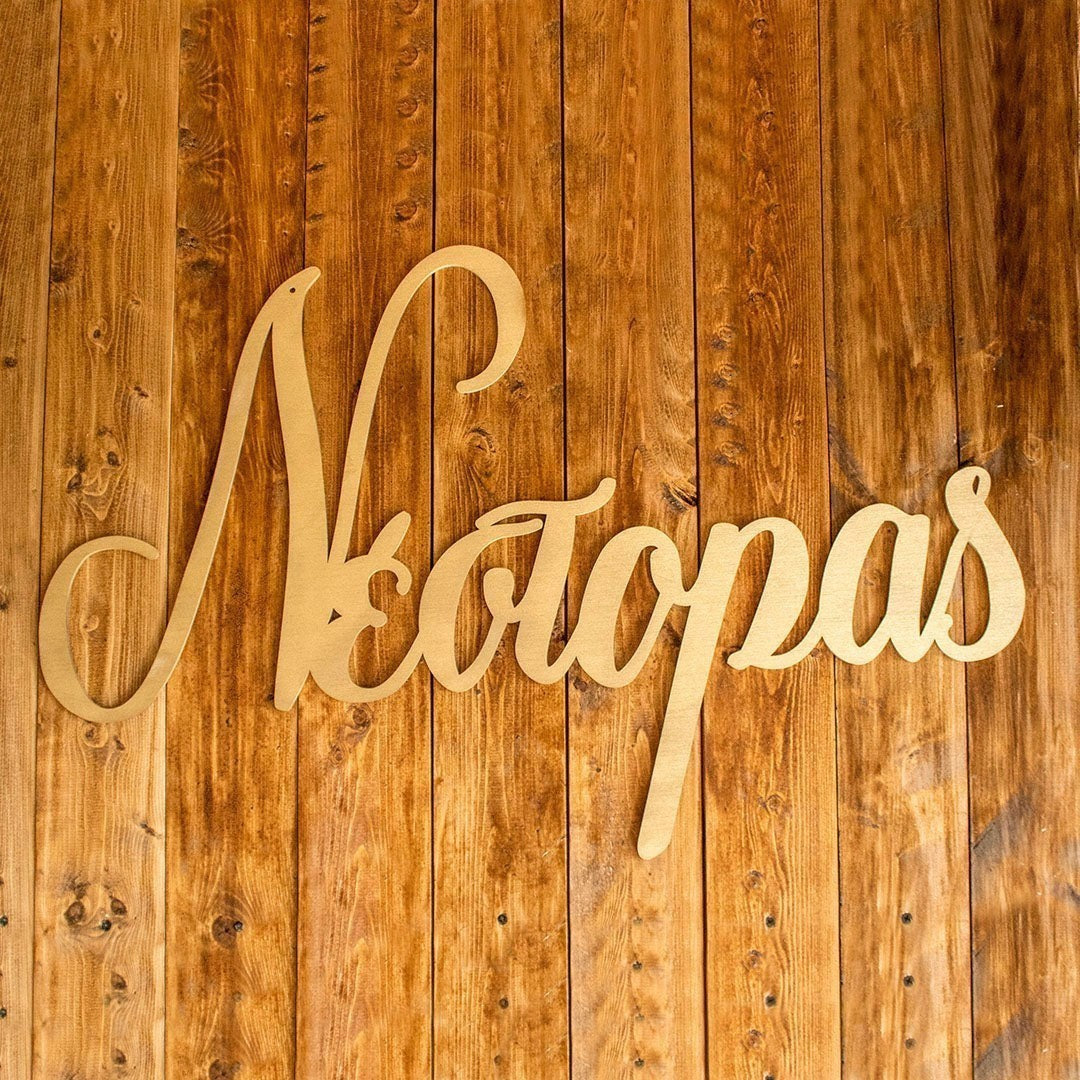 Wooderland custom laser-cut wooden name sign in raw plywood finish displayed on a rustic vertical wood plank wall