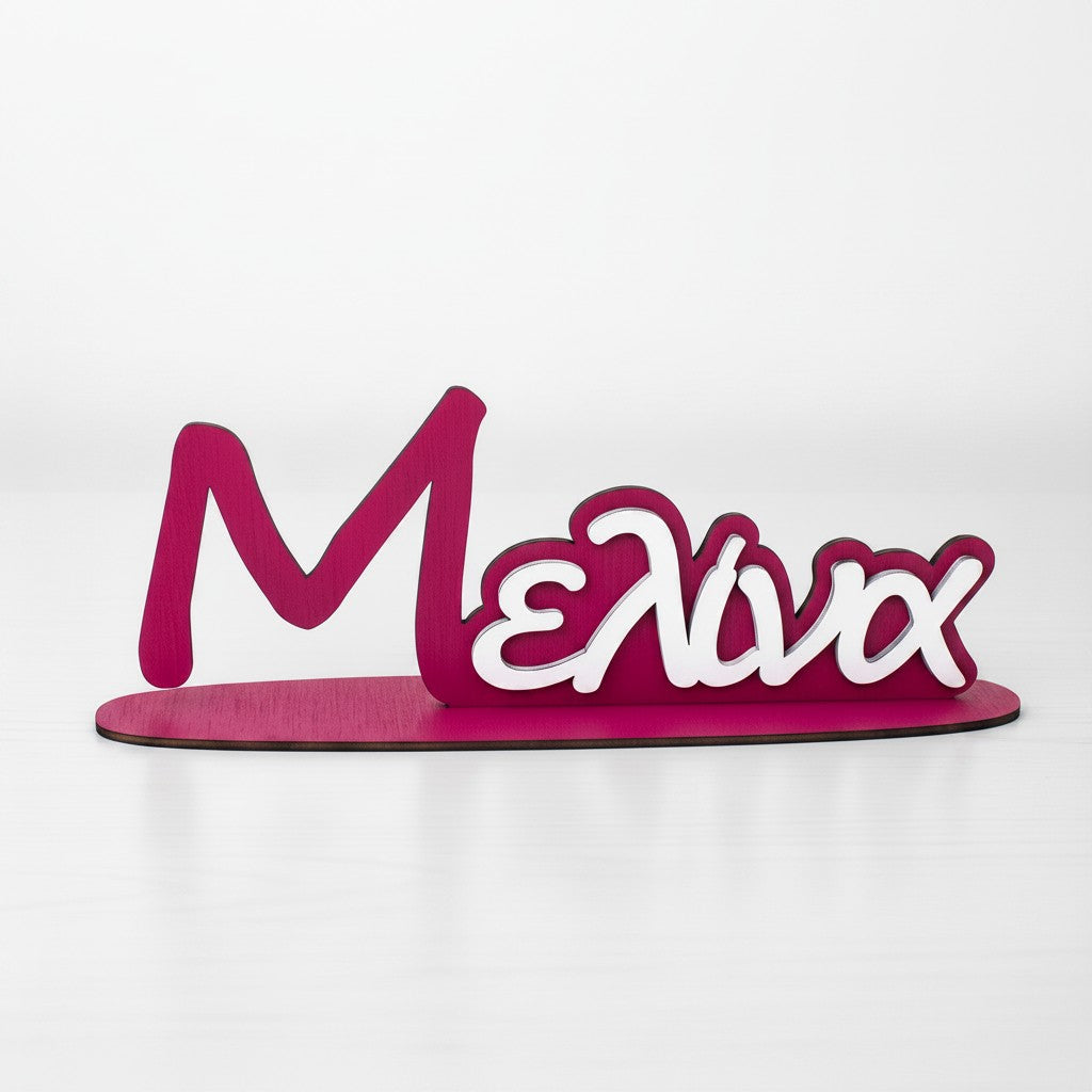 Wooderland custom two-tone wooden name sign in pink and white for a nursery or desk decor.