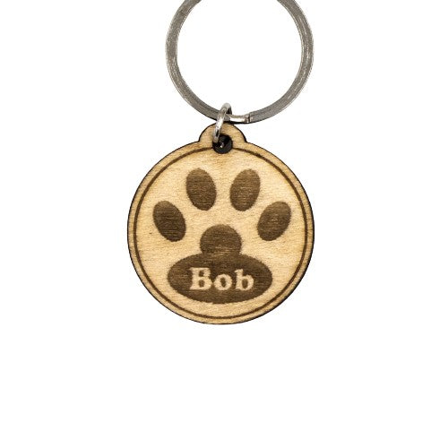 Wooderland custom round wooden dog tag with engraved paw print and the name Bob on a metal keyring