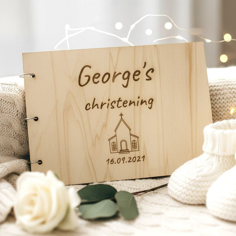 Wooderland custom engraved wooden christening wish book with baby booties and a white rose on a soft knit blanket.