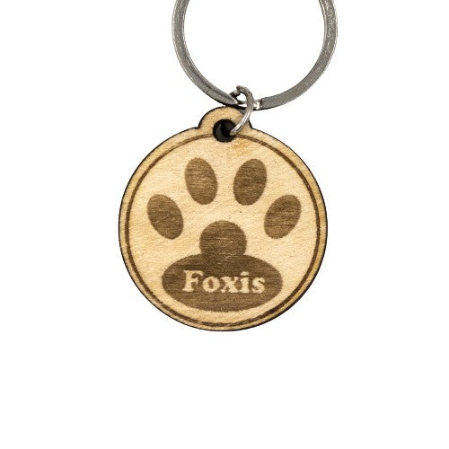 Wooderland round wooden dog tag with engraved paw print and custom name Foxis on a metal keyring