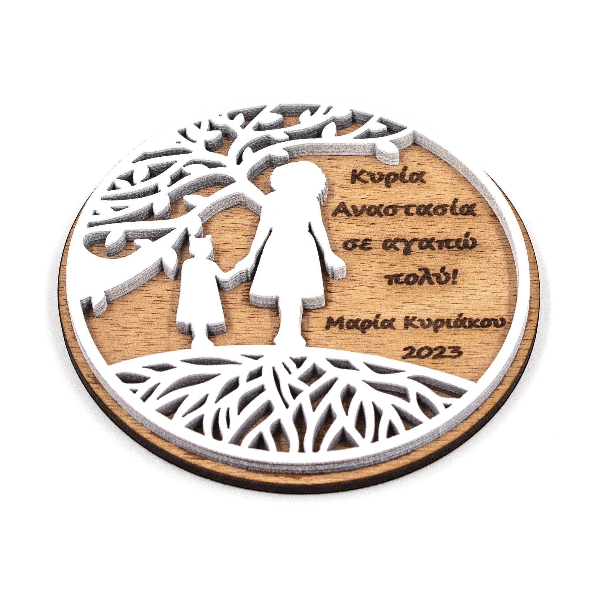 Wooderland round wooden fridge magnet featuring an engraved tree, teacher and student silhouette, and Greek text.