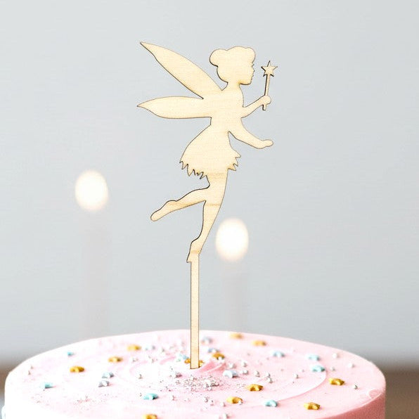 Wooderland fairy wooden cake topper on a pink birthday cake with star sprinkles for a princess themed party.