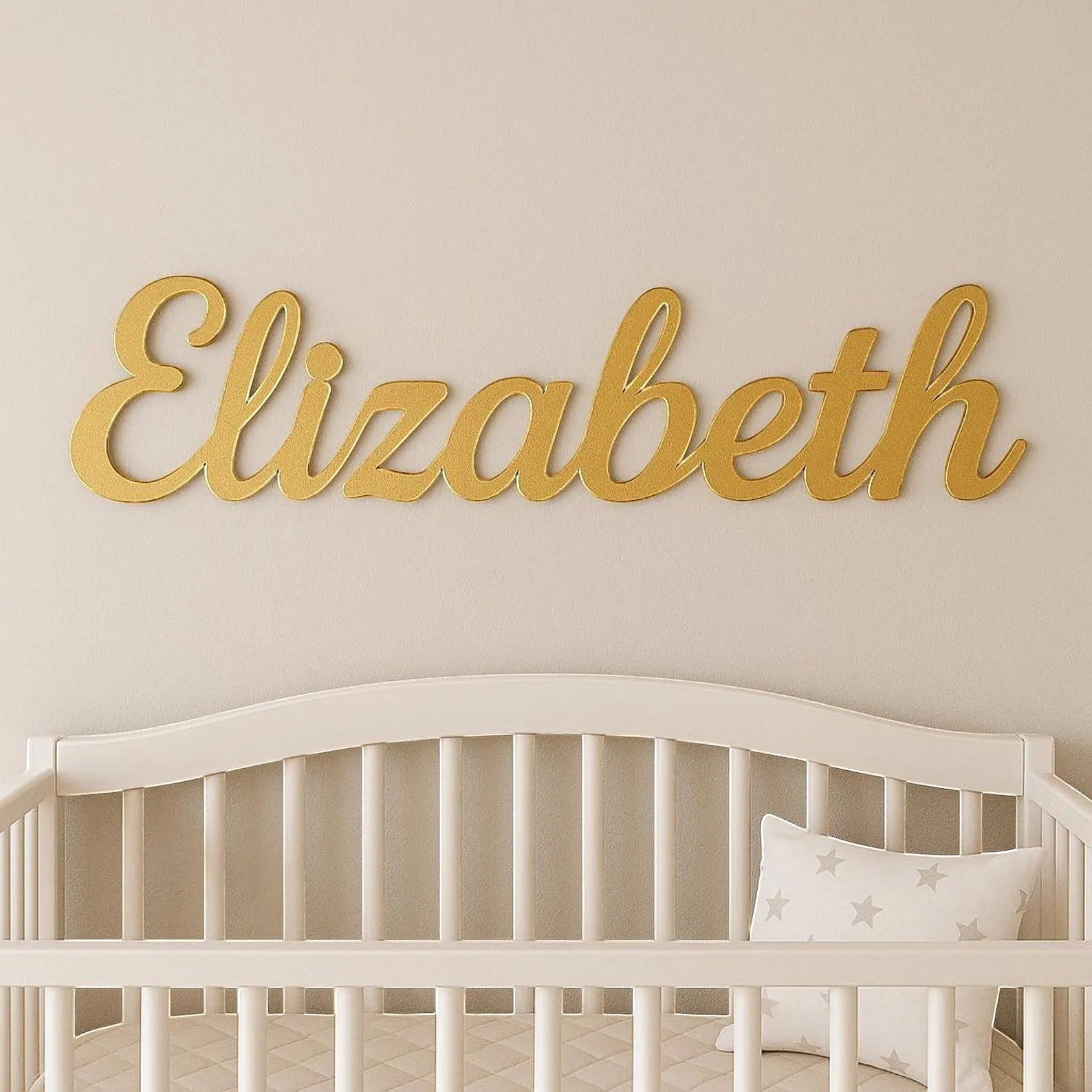 Wooderland custom gold laser-cut wooden name sign mounted on a nursery wall above a white crib.