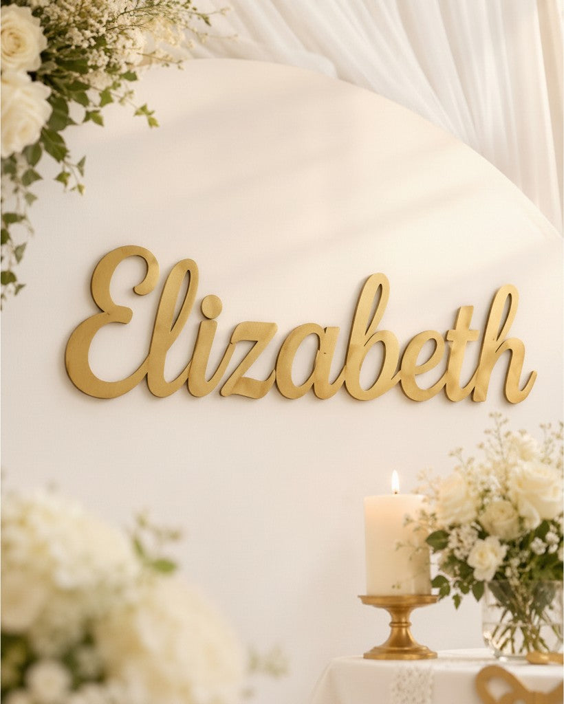 Wooderland custom gold laser-cut wooden name sign for a christening backdrop with white flowers and a candle.