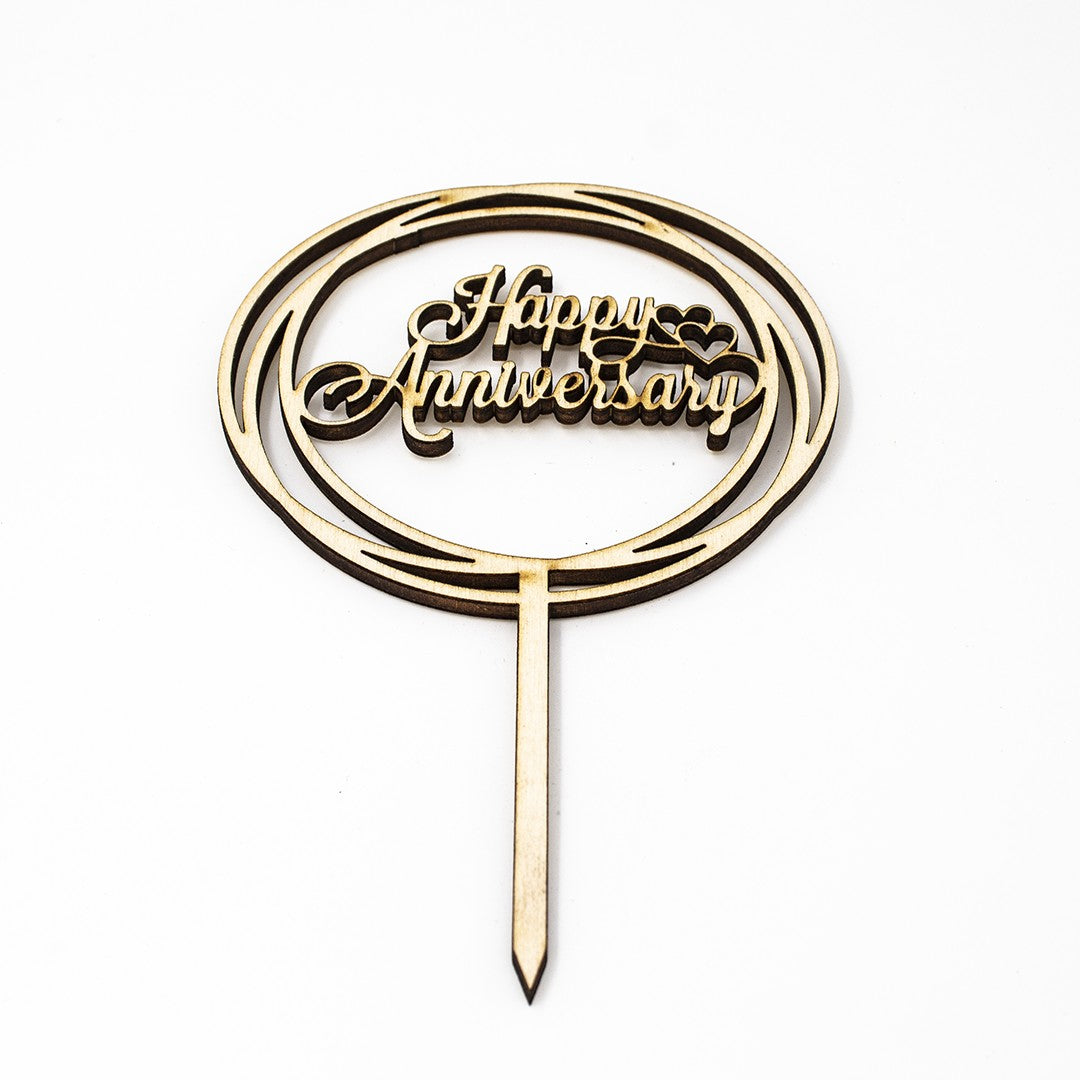 Wooderland laser-cut wooden Happy Anniversary cake topper with elegant script inside a circular frame.