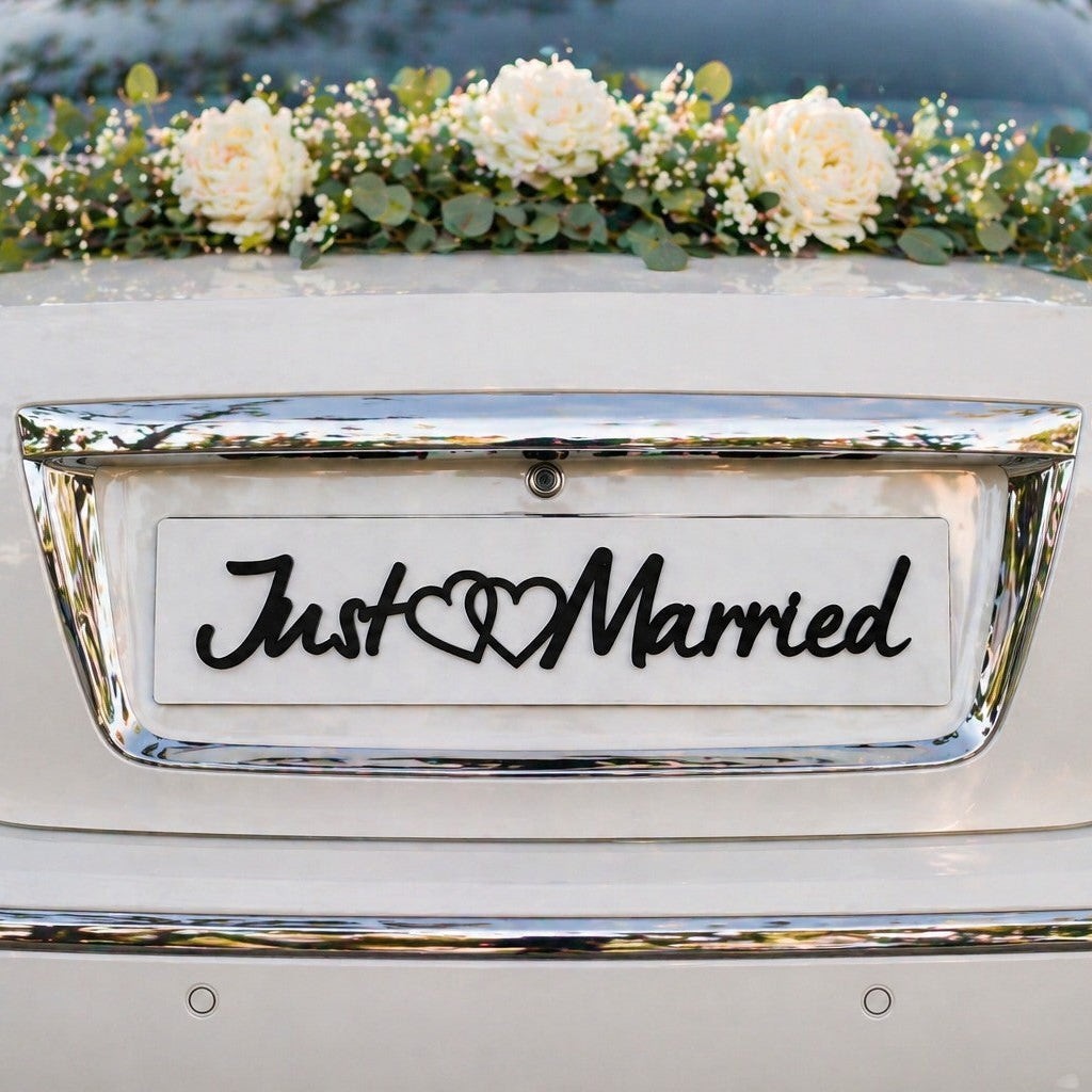 Wooderland custom wooden Just Married car plate with heart detail attached to the back of a white wedding getaway car.