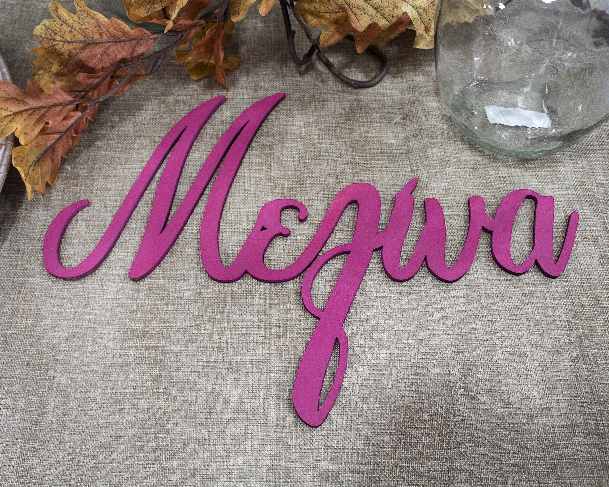 Wooderland custom laser-cut wooden name sign in magenta cursive font for christenings and baby events.