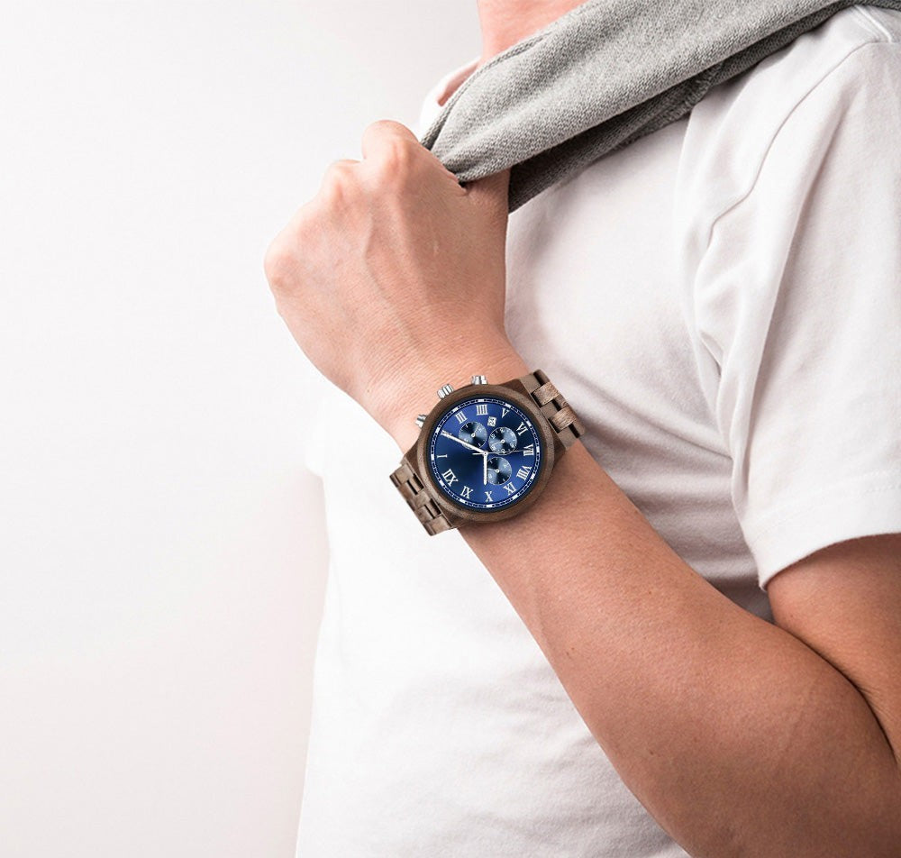 Wooderland Mars wooden watch with a blue dial and Roman numerals worn on a man's wrist with a white t-shirt