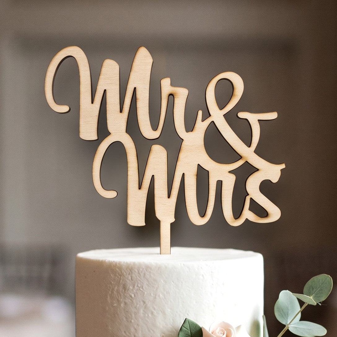 Wooderland Mr & Mrs wooden wedding cake topper in elegant laser-cut script on a three-tier white floral cake.