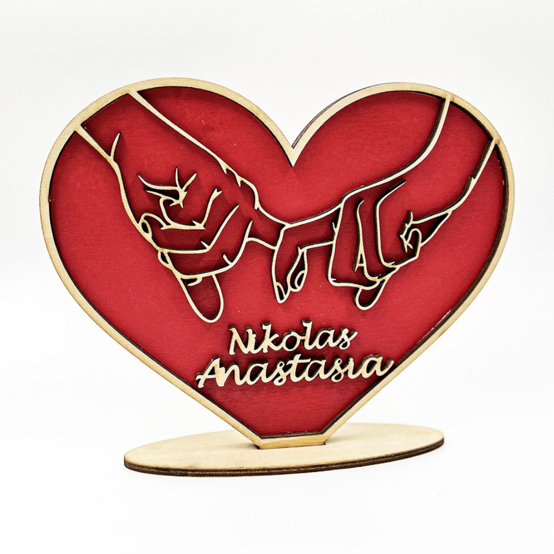 Wooderland personalized red wooden heart stand featuring carved hands holding each other with custom names engraved.