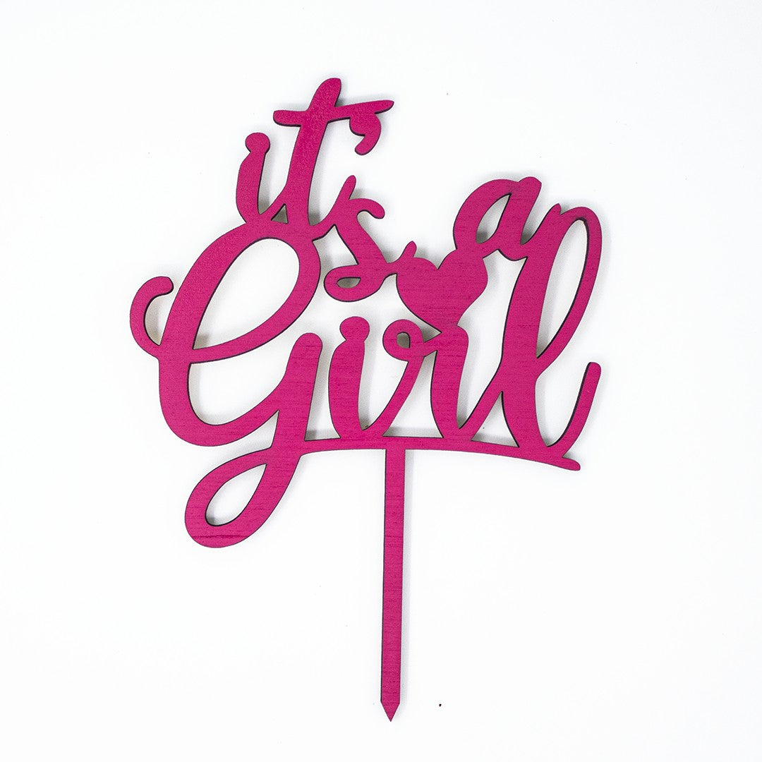 Wooderland pink wooden It's a Girl cake topper with laser-cut cursive lettering for baby showers and gender reveals.