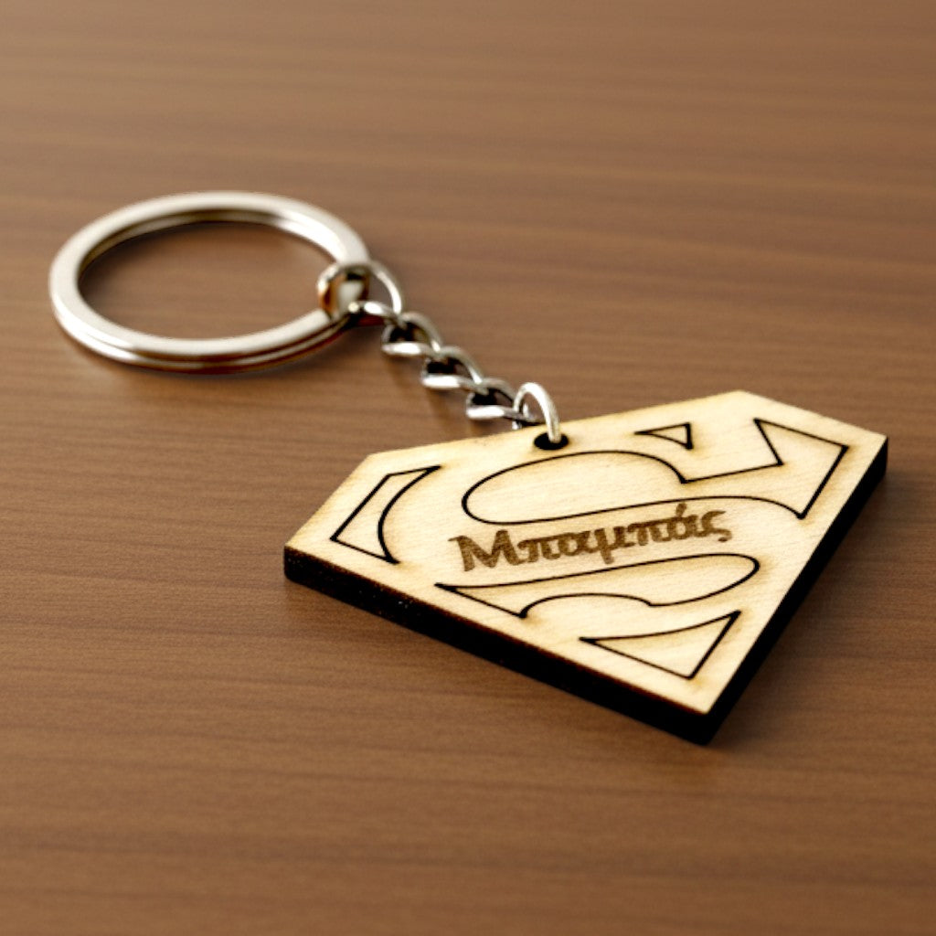 Wooderland Super Dad wooden keyring with Superman logo design and engraved Greek text on a wooden surface