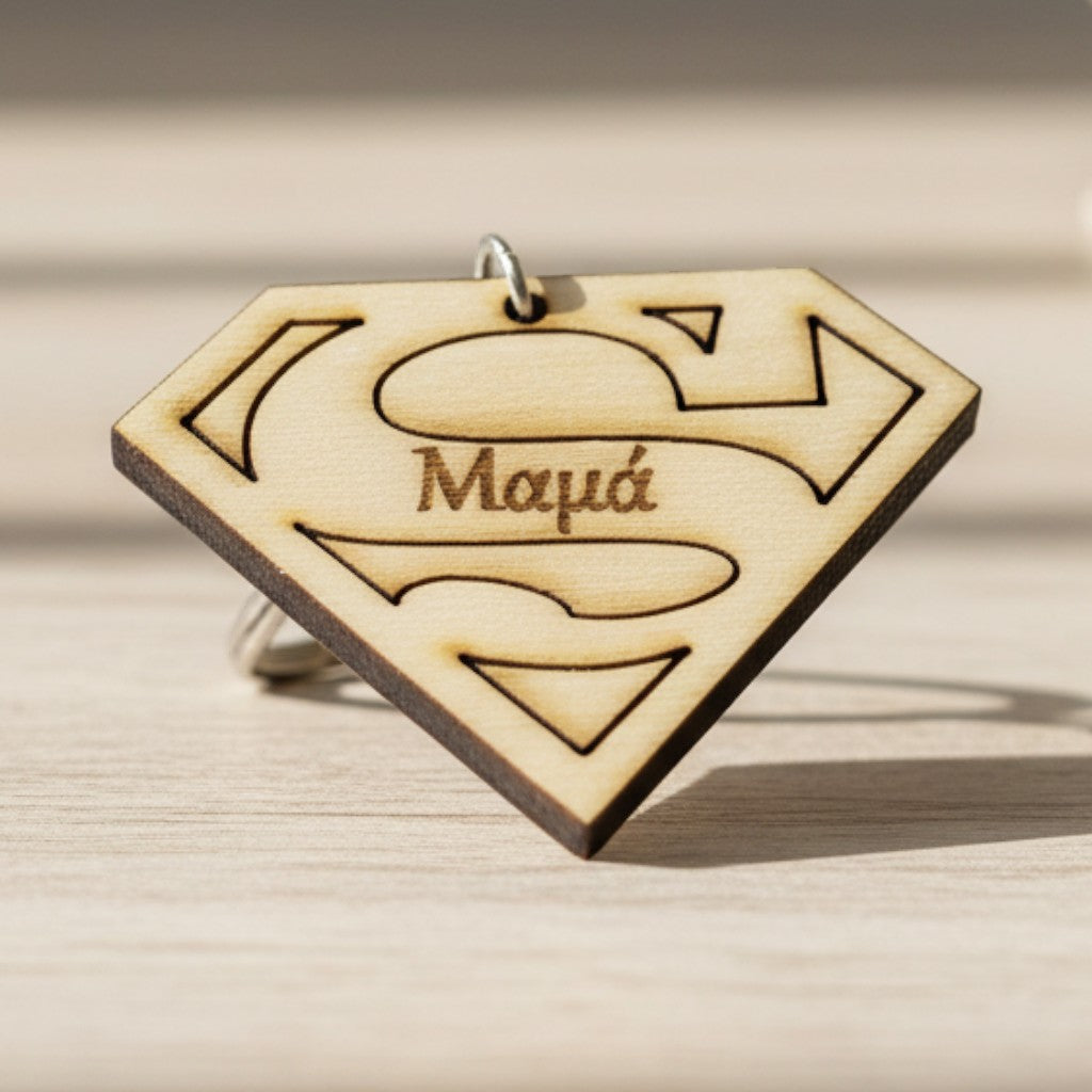 Wooderland wooden Super Mom keyring with Superman logo design and engraved Greek text on a light wooden surface