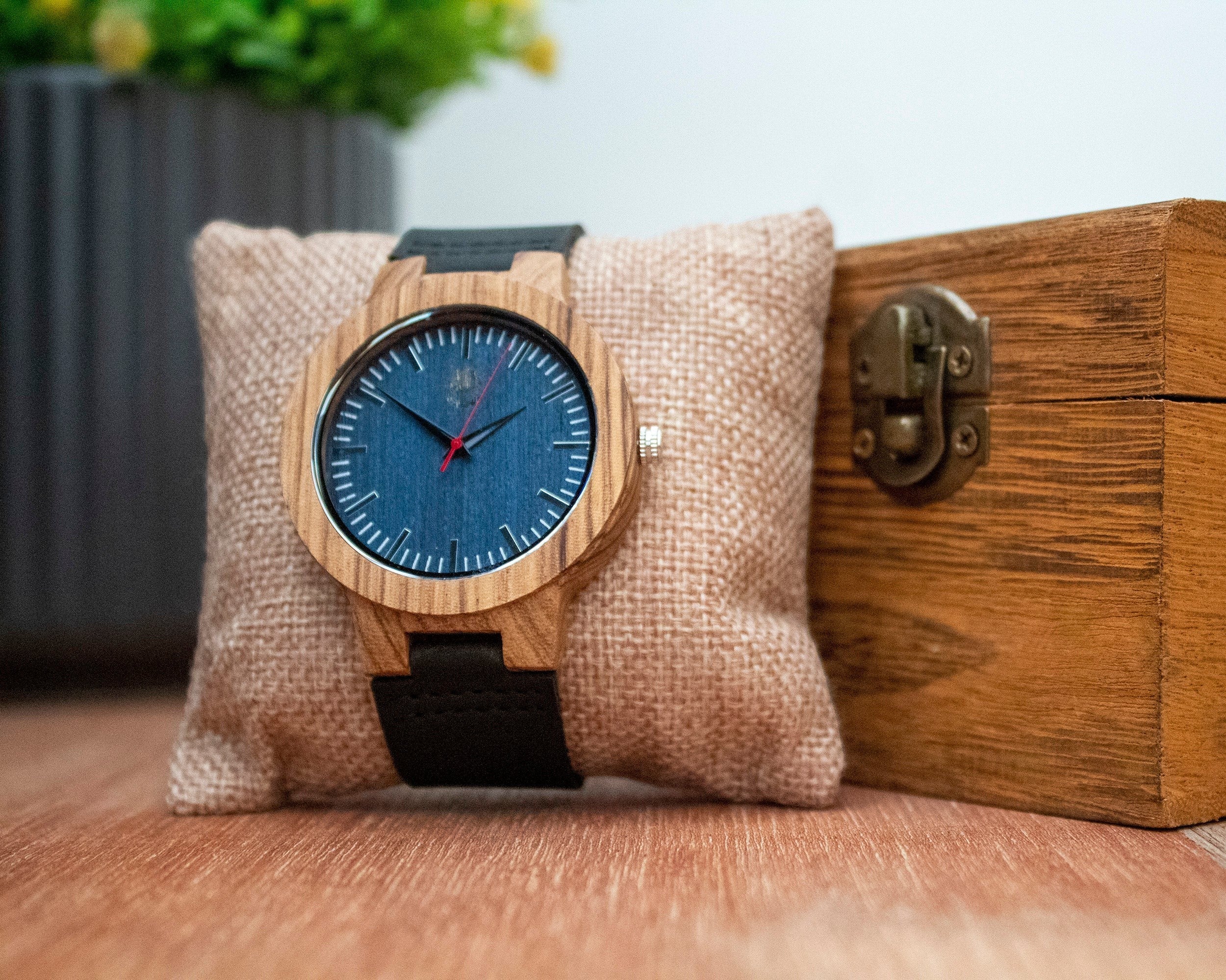 Wooderland Uranus watch with a natural wood case, blue dial, and black leather strap on a burlap display cushion.