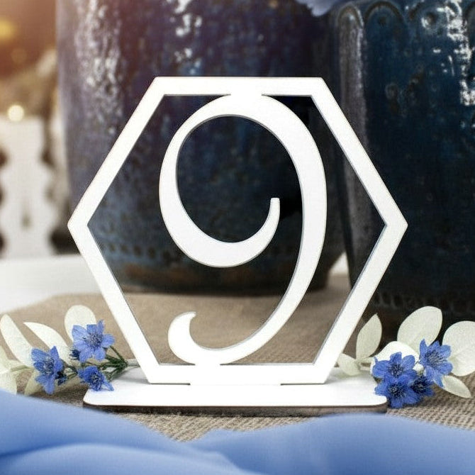 Wooderland white laser-cut wooden table number 9 in a hexagonal frame, styled on a rustic wedding table setting.