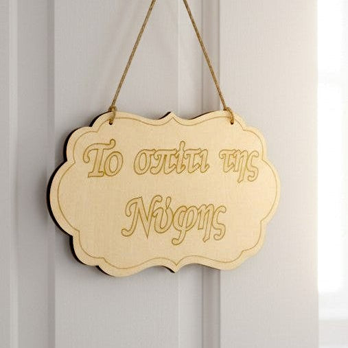 Wooderland wooden wedding label hanging on a white door with a blurred bridal gown in the background.