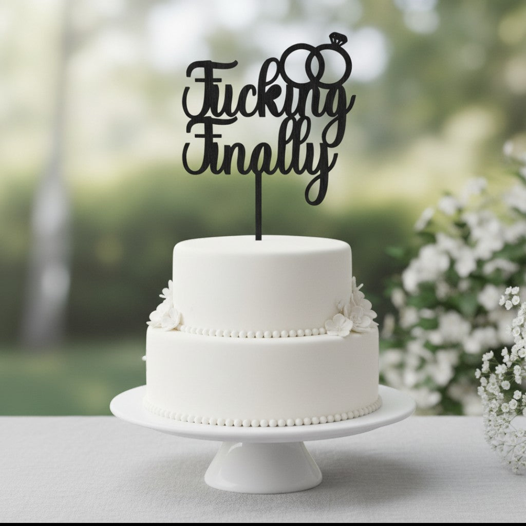 Wooderland wooden engagement cake topper with F*cking Finally text and ring icons on a white two-tier cake