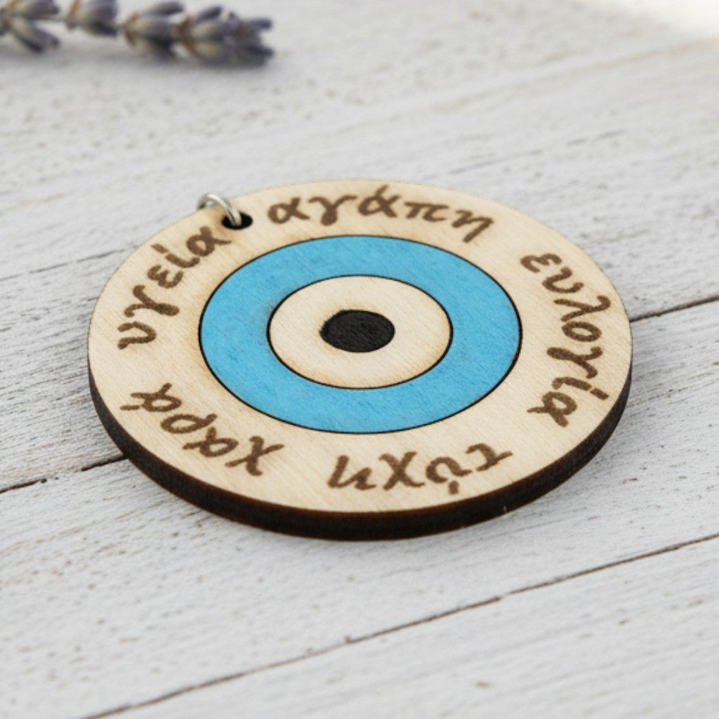 Wooderland wooden keyring featuring a blue evil eye design and engraved Greek words for love, luck, and health.