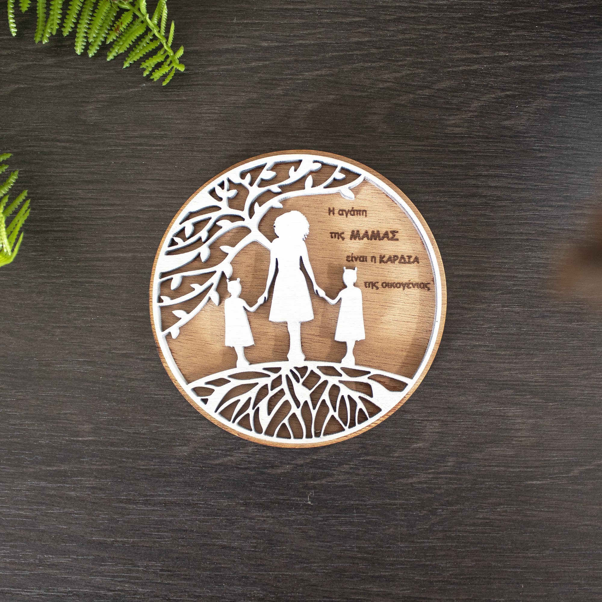 Wooderland round wooden fridge magnet featuring a white laser-cut design of a mother and two daughters under a tree.