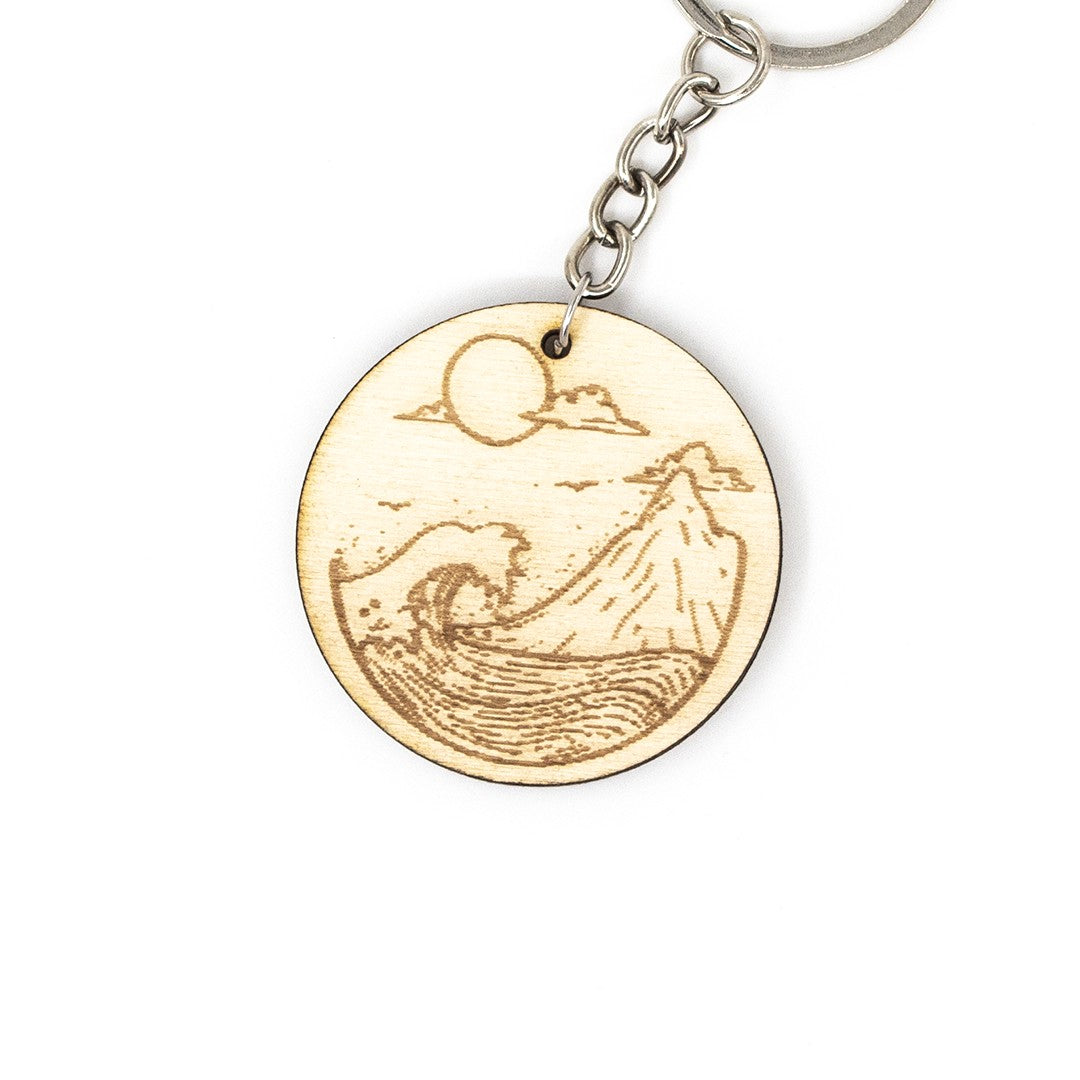 Wooderland round wooden keyring featuring a laser-engraved mountain and ocean wave design with a metal keychain ring.