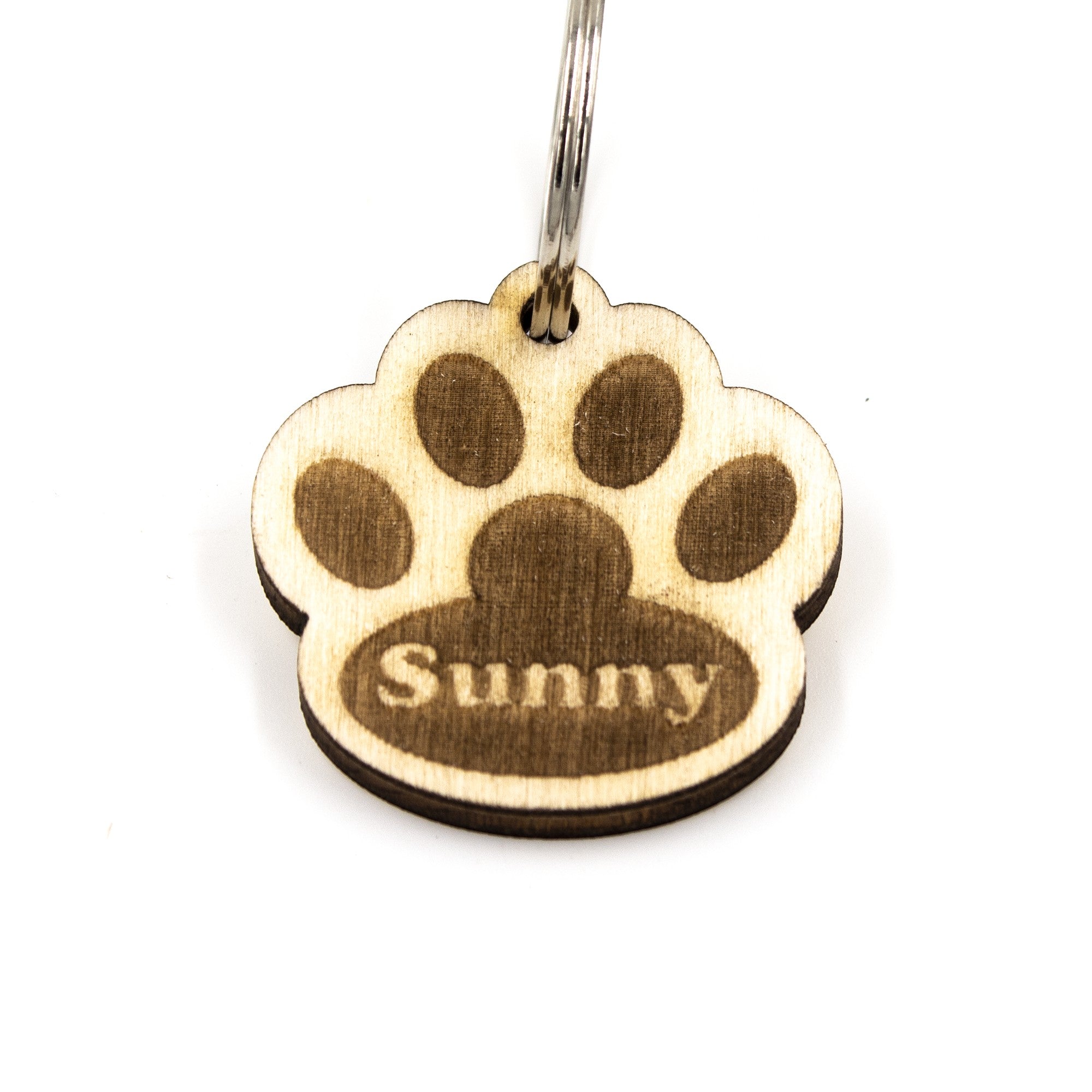 Wooderland custom wooden dog tag in a paw print shape with the name Sunny engraved on a light wood finish