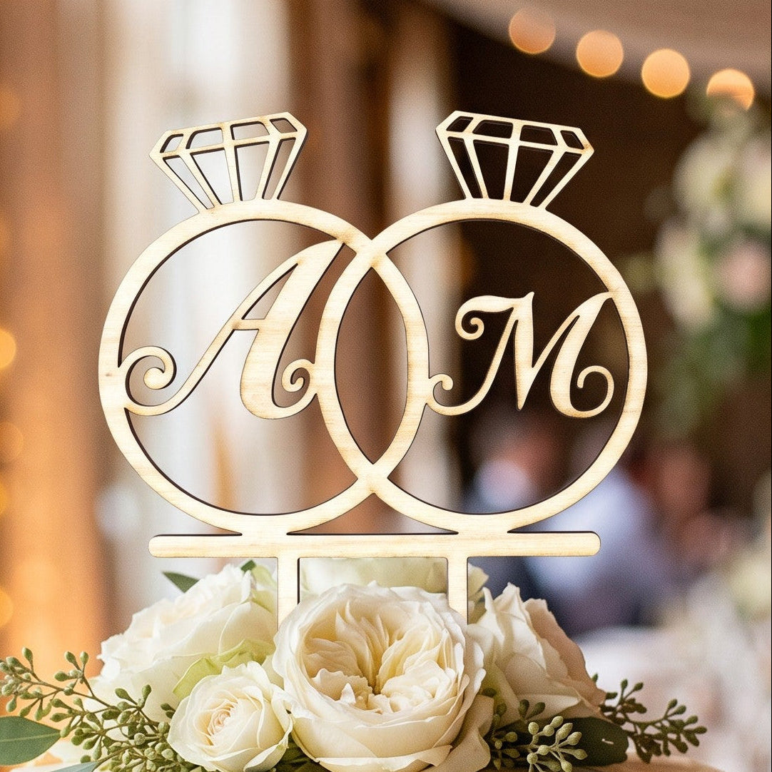 Wooderland personalized wooden wedding cake topper with interlinked rings and engraved initials on a floral cake.