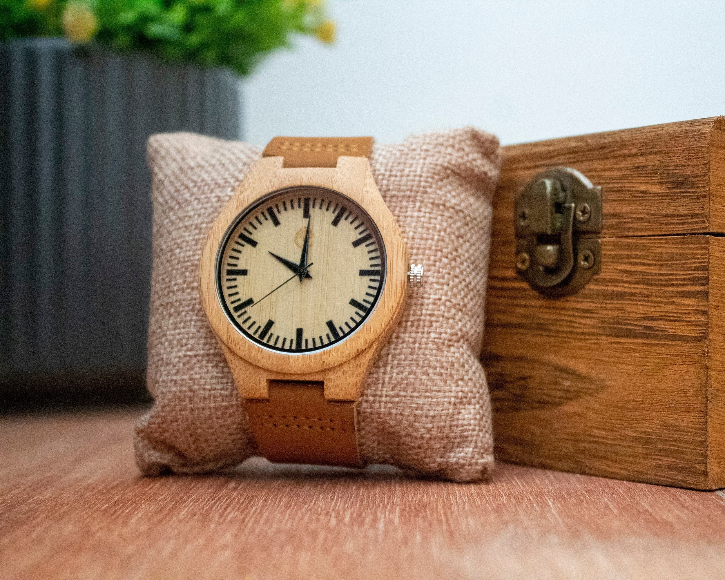 Wooderland Zeus watch with a natural light wood case, beige dial, and tan leather strap on a burlap cushion.